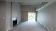 Located at 3025 E New York St in Aurora, IL, this two-story residence offers a well-appointed layout designed for comfortable everyday living. The main level showcases an open-concept kitchen and living area, where soaring vaulted ceilings lend a sense of generous vertical space. The living room is anchored by a tile-surround fireplace and features plush carpeting throughout, while sliding glass doors open to a private balcony that brings in natural light and outdoor views. The kitchen is equipped with dark cabinetry, granite-style countertops, and a breakfast bar peninsula that provides additional prep and seating space. Black appliances, including a refrigerator, range, and built-in microwave, complement the kitchen's rich, contrasting aesthetic. Track lighting illuminates both the kitchen and dining areas. Hardwood-style flooring on portions of the main level adds warmth and visual contrast to the carpeted living spaces. A staircase connects to the upper level, where a carpeted bedroom offers a quiet retreat. The bathroom features a dark-cabinet vanity with granite-style countertops, tile flooring, and a well-lit mirror. Throughout the home, neutral tones and clean lines create a cohesive, move-in-ready ambiance.
