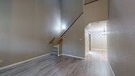 This two-story, 3-bedroom, 3-bathroom home in Modesto, California offers a well-organized layout spread across two floors. The main level is anchored by a striking open living area with soaring vaulted ceilings, neutral gray walls, and durable light-tone luxury vinyl plank flooring. A carpeted staircase with a warm wood handrail leads to the upper level, adding both visual interest and a sense of height to the space. The kitchen is thoughtfully designed with white shaker-style cabinetry, light granite countertops, stainless steel appliances, recessed lighting, and a breakfast bar peninsula — ideal for both everyday cooking and entertaining. Three full bathrooms are finished with white vanities, white countertops, brushed nickel fixtures, and vinyl plank flooring, offering a clean and cohesive aesthetic. The upper floor houses all three bedrooms, including a well-proportioned primary bedroom with natural light from a window and convenient proximity to one of the full bathrooms. Bedrooms feature plush carpet flooring. A dedicated laundry area and hallway closet add practical storage. The exterior includes a private patio enclosed by horizontal wood fencing with a gravel ground cover and a pergola overhead — a low-maintenance outdoor retreat.