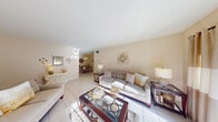 This well-appointed single-floor residence offers a cohesive, light-filled layout designed for comfortable everyday living. The spacious living room is anchored by large sliding glass doors that invite abundant natural light and provide access to an outdoor area, while light-toned ceramic tile flooring flows seamlessly throughout the main living spaces. The open layout connects the living room to a dedicated dining area, which features a pendant light fixture overhead and warm decorative accents on the walls, creating an intimate setting for meals and gatherings. The galley-style kitchen is efficiently designed with ample light wood cabinetry lining both sides, granite-toned countertops, a stainless steel sink, and white appliances including a range and refrigerator, all set on matching tile flooring. The residence includes two well-proportioned bedrooms, each with ceiling fans and natural light. The primary bedroom features warm hardwood-style flooring, while the second bedroom offers a cozy and serene atmosphere. The full bathroom is finished with large-format tile surrounds and includes a walk-in glass-enclosed shower. Throughout the home, a consistent warm beige palette and thoughtful design details contribute to a calm, inviting ambiance.
