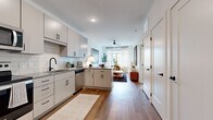 Located at 423 E 36th Street in Charlotte's vibrant 28205 corridor, this single-floor residence offers a thoughtfully designed open-concept layout with clean, modern finishes. Rich hardwood-style flooring runs throughout the main living areas, anchoring the space with warmth and continuity.

The kitchen serves as a functional centerpiece, outfitted with light gray flat-front cabinetry, stainless steel Whirlpool appliances, a subway tile backsplash, and a gray quartz peninsula with bar seating — ideal for casual dining or entertaining. A deep undermount sink with a matte black faucet adds a refined contrast to the neutral palette.

The open living area benefits from large windows that invite generous natural light, with views of the surrounding Charlotte streetscape. A ceiling fan overhead and sheer drapery contribute to a bright, airy ambiance.

The bedroom is a calm retreat featuring windows with city views, crisp white walls, and plush carpeting. The bathroom is finished with matching gray cabinetry, quartz countertops, wood-look tile flooring, and a glass-enclosed walk-in shower, all accented with matte black hardware for a cohesive, contemporary aesthetic throughout.