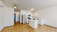Located at 6516 E Fourth Ave in Spokane Valley, WA, this single-level, 2-bedroom, 2-bathroom unit offers a well-designed layout with clean, modern finishes throughout. The open-concept kitchen and living area serves as the heart of the space, featuring crisp white shaker cabinetry, light countertops, and a full suite of stainless steel appliances including a refrigerator, range, microwave, and dishwasher. A central kitchen island provides additional prep and counter space. Light-toned, hardwood-style flooring runs throughout the main living areas, lending a bright and cohesive feel. The living room benefits from a large window that allows natural light to fill the space, with a front entry door nearby. Both bedrooms are carpeted for comfort and feature windows with views of the surrounding greenery; the primary bedroom includes a sliding glass door that opens to a private outdoor area. Each bathroom is well-appointed — one features a corner walk-in shower, white vanity cabinetry, and hardwood-style flooring. A dedicated laundry room includes a full-size washer and dryer with overhead shelving for added storage. The overall aesthetic is clean, contemporary, and functional throughout.