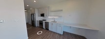 This 330 square foot apartment offers a thoughtfully designed living space that maximizes functionality in a compact area. The layout includes two distinct kitchen areas and one well-appointed bathroom, creating a unique and versatile living environment.

The kitchens showcase modern design with white cabinetry, stainless steel appliances, and subway tile backsplashes. Quartz countertops provide ample workspace, while the sleek fixtures and hardware add a contemporary touch. One kitchen features a full-size refrigerator and range, while the other offers additional storage and preparation space.

The bathroom is efficiently designed with a single vanity, toilet, and likely a shower (not visible in the image). Light-colored walls and a large mirror create a sense of spaciousness, while the wood-look flooring adds warmth to the space.

Throughout the apartment, wood-look flooring creates a cohesive and inviting atmosphere. Large windows allow for abundant natural light, brightening the interior and offering views of the surrounding area. The open layout promotes a sense of spaciousness despite the compact square footage.

This apartment combines modern aesthetics with practical design, ideal for those seeking an efficient urban living space with contemporary amenities.