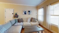 Located at 2900 E North St in Greenville, South Carolina, this single-floor residence offers a well-designed layout that balances comfort and functionality. The living room is a welcoming gathering space, highlighted by warm hardwood floors, crown molding, and multiple windows fitted with blinds and sheer curtains that allow generous natural light to fill the room. A large sectional sofa, coffee table, and wall-mounted television make it an ideal space for relaxing or entertaining.

The kitchen is a standout feature, centered around a granite-topped island with a built-in sink and pendant lighting overhead. Dark espresso cabinetry provides ample storage, while stainless steel appliances — including a refrigerator, microwave, and range — complete the space. The kitchen flows seamlessly into a dedicated dining and work nook, accented by hardwood floors and decorative wall art.

The bedrooms are carpeted for comfort, each offering a ceiling fan and access to natural light. A bathroom adjacent to the main living areas features granite countertops, dark wood cabinetry, a large vanity mirror, and hardwood flooring. Throughout the residence, crown molding and neutral warm-toned walls create a cohesive, inviting atmosphere suited for everyday living.