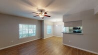 This single-story residence in Humble, Texas offers a practical and well-organized layout across two bedrooms and two bathrooms. The open living and dining area is finished with warm wood-look flooring and features a ceiling fan with light kit, multiple windows with blinds that invite natural light, and a pendant light marking the dining space. A pass-through breakfast bar connects the living area to the galley-style kitchen, which is lined with gray-toned cabinetry, granite-look countertops, and stainless steel appliances including a range, microwave, and refrigerator. A utility closet is accessible from the kitchen hallway.

Both bedrooms are carpeted and include ceiling fans. The primary bedroom features a vaulted ceiling, a sliding glass door with outdoor views, a walk-in closet, and an en-suite bathroom. The second bedroom offers generous closet space with mirrored sliding doors. Both bathrooms are finished with wood-look flooring, vanities with storage cabinetry, and lighted mirrors. The overall color palette is neutral throughout, with gray walls and white trim lending a clean, cohesive aesthetic to the entire space.