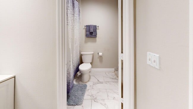Elegante baño con accesorios modernos, que incluye una elegante cortina de ducha y suelo de baldosas pulidas. - Chateau of Tampa