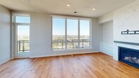 Located at 200 University Ave SE in Minneapolis, this well-appointed 2-bedroom, 5-bathroom residence offers generous single-floor living with refined finishes throughout. The open living room is anchored by a striking marble-surround fireplace and warm hardwood flooring, with sliding glass doors opening to a private balcony showcasing sweeping city and treetop views. The dining area features the same rich hardwood floors and is illuminated by an elegant sculptural chandelier and large windows that invite abundant natural light. The gourmet kitchen is outfitted with white shaker cabinetry, a large quartz island, stainless steel appliances including double wall ovens and a gas cooktop, a mosaic tile backsplash, and a picture window framing panoramic views. The expansive primary bedroom is carpeted and includes a ceiling fan and access to a generous walk-in closet with custom built-in shelving. The luxurious primary bathrooms are clad in large-format marble-look tile, featuring a freestanding soaking tub, a glass-enclosed walk-in shower, and a lengthy double vanity. A dedicated laundry room with stacked washer and dryer and hardwood floors adds everyday convenience. The overall aesthetic is modern and sophisticated, with a neutral palette enhancing the bright, airy atmosphere throughout.