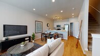 This two-story residence is designed with a clean, contemporary aesthetic and thoughtful layout across both levels. The main living area presents an open-concept floor plan where the living room, dining area, and kitchen flow seamlessly together. Light hardwood flooring runs throughout, complementing neutral gray-toned walls and recessed lighting that brightens the entire space. A large window in the living area allows natural light to fill the room, enhancing its welcoming ambiance.

The kitchen is outfitted with white shaker-style cabinetry extending to the ceiling for ample storage, white countertops, and a full suite of stainless steel appliances including a refrigerator, range, and microwave. A peninsula with bar seating connects the kitchen to the dining and living areas, reinforcing the open layout. A dedicated pantry closet with wire shelving provides additional storage just off the kitchen.

The bedrooms, located on the upper level, are carpeted for comfort and feature neutral tones and good natural light from multiple windows. The primary bedroom includes a spacious walk-in closet with wire shelving systems. The bathroom presents a streamlined design with a white vanity, wood-look flooring, and clean, understated finishes. Overall, the space offers a well-balanced combination of functionality and modern style.