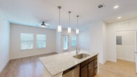 Located in Killeen, TX, this one-bedroom, one-bathroom unit offers a thoughtfully designed single-floor layout that makes efficient use of its space. The open-concept kitchen and living area serves as the heart of the home, anchored by a large central island with granite countertops, an undermount sink, and pendant lighting overhead. Dark espresso cabinetry contrasts beautifully with the light granite surfaces, while stainless steel appliances — including a refrigerator, range, microwave, and dishwasher — complete the kitchen. Light wood-style flooring flows throughout the main living areas, complemented by a ceiling fan and multiple windows dressed with blinds that invite natural light. The bedroom features plush carpeting, a ceiling fan, and a window overlooking the exterior, with direct access to a walk-in closet equipped with built-in shelving for ample storage. The bathroom mirrors the kitchen's design aesthetic with matching dark cabinetry, granite countertops, a large vanity mirror, and a full shower-tub combination. A dedicated laundry area with overhead shelving adds everyday convenience, rounding out this well-appointed and functional living space.