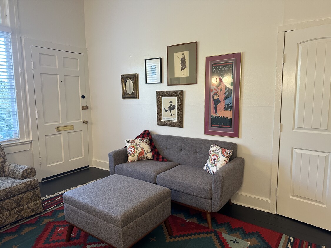 Living area with sofa, armchair, and storage ottoman. - 1314 Pleasant St