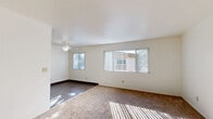 Located at 7844 Paradise Valley Road in San Diego, CA, this single-story home offers a practical and comfortable layout across three bedrooms and one bathroom. The living room is a bright, open space featuring carpet flooring, a ceiling fan, and multiple windows dressed with vertical blinds that invite generous natural light and outdoor views. The flooring transitions from carpet to hardwood-style in the dining area, which flows seamlessly into the kitchen — a functional space with warm wood-toned cabinetry. A central hallway connects the main living areas to the three bedrooms, each finished with plush carpet, ceiling fans, and windows overlooking the surroundings. The bedrooms are equipped with built-in closets featuring open shelving units, offering organized storage solutions. The bathroom includes a full soaking tub framed by speckled stone-look surround walls, adding a durable and clean aesthetic. White walls throughout the home create a bright, neutral backdrop that enhances the sense of space. The layout is efficiently designed, making the most of every room while maintaining a cohesive, easy-flowing floor plan suited for everyday living.