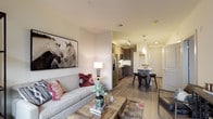 This thoughtfully designed single-floor residence offers a seamless blend of modern style and functional living. The open-concept layout connects the living room, dining area, and kitchen, creating a bright and cohesive space anchored by wood-look plank flooring throughout.

The living room is generously sized, featuring large windows and a glass door that open to a private balcony, flooding the space with natural light and providing pleasant outdoor views. The kitchen is a standout feature, showcasing dark espresso cabinetry, stainless steel appliances including a refrigerator, range, and built-in microwave, as well as a granite-topped island with bar seating — ideal for both cooking and casual dining. Elegant pendant lighting and under-cabinet illumination enhance the kitchen's contemporary aesthetic.

The bedroom offers a comfortable retreat, complete with plush carpeting, a large window with outdoor views, and wall-mounted shelving for added storage. An en-suite bathroom features a granite vanity with dark cabinetry, a large mirror with bar lighting, tile flooring, and a combination tub and shower. A walk-in closet provides practical storage just off the bedroom.

Throughout the residence, neutral tones, clean lines, and quality finishes contribute to a polished yet welcoming ambiance.
