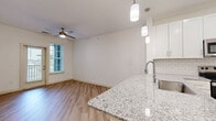 This 580 square foot apartment in Glen Allen, VA, offers a thoughtful design that maximizes space and functionality. The single-floor layout includes one bedroom, measuring 130 square feet, providing a cozy retreat. The bathroom features a clean, white aesthetic with a full-size bathtub and modern fixtures. 

The kitchen is a highlight, boasting sleek white cabinetry, granite countertops, and stainless steel appliances, including a microwave and refrigerator. A central island with a sink serves as both a prep area and a visual divide between the kitchen and living space. The open-concept design is enhanced by recessed lighting and pendant fixtures, creating a bright and airy atmosphere.

Throughout the apartment, you'll find a mix of flooring materials. The bedroom is carpeted for comfort, while the main living areas and kitchen feature durable, wood-look flooring. Large windows in the bedroom allow natural light to flood the space, and are fitted with blinds for privacy.

The unit includes in-apartment laundry facilities, a convenience that adds significant value to the compact living space. Clean lines, neutral colors, and modern finishes create a contemporary feel throughout, making this apartment an ideal choice for those seeking efficient, stylish living in Glen Allen.