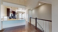 This three-story home offers a thoughtfully designed layout with quality finishes carried consistently throughout each level. Rich hardwood flooring flows across the main living areas, complemented by neutral wall tones that create a clean, modern aesthetic. The main living space is bright and open, with large windows that invite natural light and a staircase featuring a classic dark wood newel post and white baluster railing.

The kitchen is a standout feature, showcasing rich dark cabinetry, granite countertops, a large center island, and stainless steel appliances including a refrigerator, range, and dishwasher. Brushed nickel pendant lights hang above the island, adding both task lighting and style. A tray ceiling with track lighting further elevates the kitchen's character.

Additional living areas offer generous proportions, recessed lighting, and large windows with blinds. Bedrooms are spacious and well-lit, with ceiling fans and convenient access to closets and hallways. The bathrooms are finished with tile flooring, granite vanity tops, dark cabinetry, and tiled tub-shower combinations. Carpeted staircases with dark wood handrails connect all three floors, ensuring a cohesive design from top to bottom throughout the home.