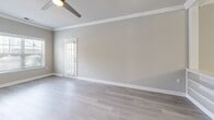 This well-appointed 3-bedroom, 2-bathroom home in Wilmington, NC offers a thoughtfully designed single-floor layout with a clean, modern aesthetic throughout. The living room features light hardwood-style flooring, crown molding, a ceiling fan, and a door opening to one of two balconies, filling the space with natural light. The adjacent dining area is defined by decorative columns, additional crown molding, and an elegant chandelier, creating a refined yet open atmosphere. The kitchen is equipped with white shaker-style cabinetry, stone countertops, a classic white tile backsplash, and stainless steel appliances, including a refrigerator, dishwasher, range, and microwave. Both bathrooms are finished with white vanity cabinetry, stone countertops, and framed mirrors, with light hardwood-style flooring adding a cohesive feel. The spacious primary bedroom offers plush carpeting and a generous walk-in closet with wire shelving. The additional bedrooms are also carpeted and include their own closets. A dedicated laundry room with a full-size washer and dryer adds everyday convenience. With four closets and a utility room, storage is plentiful throughout this well-organized home.