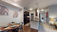 Located at 4000 Mullan Road in Missoula, Montana, this single-floor residence offers a thoughtfully designed layout that balances comfort and functionality. The open-concept kitchen is a standout feature, boasting dark espresso cabinetry, granite-style countertops, black appliances, under-cabinet lighting, and a convenient walk-in pantry. A breakfast bar with pendant lighting connects the kitchen to the dining area, which features warm wood-look flooring and a tray ceiling detail. The living room is generously sized with plush carpet, soft blue-gray accent walls, and large sliding glass doors that flood the space with natural light and provide direct access to a private outdoor patio. A secondary flex room with coordinating blue tones offers additional versatile living space. The bedroom features carpet flooring, warm-toned walls, and a horizontal window for natural light. The bathrooms are well-equipped, including a full bath with dark wood vanity, granite countertop, wood-look tile flooring, and a walk-in shower with curtain enclosure. Throughout the residence, a cohesive modern-casual aesthetic is maintained with consistent finishes, creating a welcoming and practical home.
