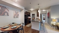 Located at 4000 Mullan Road in Missoula, Montana, this single-floor residence offers a thoughtfully designed layout that balances comfort and functionality. The open-concept kitchen is a standout feature, boasting dark espresso cabinetry, granite-style countertops, black appliances, under-cabinet lighting, and a convenient walk-in pantry. A breakfast bar with pendant lighting connects the kitchen to the dining area, which features warm wood-look flooring and a tray ceiling detail. The living room is generously sized with plush carpet, soft blue-gray accent walls, and large sliding glass doors that flood the space with natural light and provide direct access to a private outdoor patio. A secondary flex room with coordinating blue tones offers additional versatile living space. The bedroom features carpet flooring, warm-toned walls, and a horizontal window for natural light. The bathrooms are well-equipped, including a full bath with dark wood vanity, granite countertop, wood-look tile flooring, and a walk-in shower with curtain enclosure. Throughout the residence, a cohesive modern-casual aesthetic is maintained with consistent finishes, creating a welcoming and practical home.