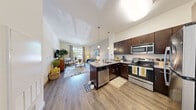 This thoughtfully designed 1-bedroom, 1-bathroom residence offers a cohesive open-concept layout that maximizes every square foot. The kitchen and living area flow seamlessly together, anchored by a central island with granite countertops, pendant lighting, and bar seating — ideal for casual dining or entertaining. Rich dark-wood cabinetry pairs with a full suite of stainless steel appliances, including a refrigerator, range, microwave, and dishwasher, while light hardwood-style flooring ties the space together. The living area is generously proportioned, featuring large windows that invite abundant natural light and provide outdoor views. Neutral wall tones create a versatile backdrop throughout.

The bedroom offers a comfortable, carpeted retreat with a large closet, a bright window with outdoor views, and soft, neutral tones on the walls. The bathroom continues the upscale finish level with a granite-topped dark vanity, an undermount sink, and a well-lit mirror. A dedicated entryway provides a clean transition into the home. Throughout the residence, the consistent use of granite surfaces, dark cabinetry, and wood-tone flooring lends a unified, modern aesthetic that balances style with everyday functionality.