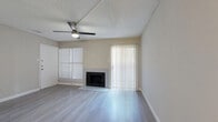 This single-floor, 1-bedroom, 1-bathroom residence offers a thoughtfully organized layout across a compact yet functional footprint. The combined kitchen and living area serves as the heart of the home, where light wood-style flooring, neutral-toned walls, and a textured ceiling create a clean, cohesive aesthetic. The living area is highlighted by a built-in fireplace, a ceiling fan with integrated lighting, and dual window treatments — including a sliding glass door with vertical blinds that provides access to an outdoor area and allows for generous natural light. The kitchen is well-equipped with white shaker-style cabinetry, a classic white subway tile backsplash, stainless steel appliances including a range, over-the-range microwave, and dishwasher, all set over matching light hardwood-style flooring. The bedroom is a comfortable, well-proportioned space featuring a ceiling fan, a window with blinds, and direct access to a dedicated walk-in closet outfitted with built-in shelving. The bathroom includes a full tub-shower combination with tiled surround. A hallway connects the main living spaces efficiently, rounding out a practical and move-in-ready floor plan.
