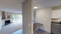 Located at 2600 Raintree Dr in Fort Collins, Colorado, this single-floor unit offers a well-organized layout connecting living, dining, kitchen, and bedroom spaces in a cohesive flow. The living room serves as the centerpiece of the unit, featuring a corner fireplace with a raised hearth, plush wall-to-wall carpeting, a baseboard heating system, and a large sliding glass door that opens to a private balcony with views of mature greenery. Natural light filters generously into this space, creating a bright and welcoming atmosphere.

The kitchen is efficiently designed with white shaker-style cabinetry, dark granite-look countertops, and black appliances including a range, refrigerator, and dishwasher. Wood-look vinyl plank flooring extends through the kitchen and entry areas, providing a clean contrast to the carpeted living spaces. A peninsula counter connects the kitchen to the adjoining area, enhancing functionality.

The bedroom is a quiet, comfortable space with plush carpeting, a ceiling light fixture, and a window framing outdoor views. The bathroom features a full tub and shower combination with clean white tile surround and brushed nickel fixtures. Textured ceilings are consistent throughout the unit.