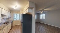 This single-floor unit offers a thoughtfully designed open-concept layout that seamlessly connects the kitchen and living areas. The kitchen is a standout feature, showcasing white shaker cabinetry, sleek gray quartz-style countertops, a subway tile backsplash, a stainless steel undermount sink, and stainless steel appliances including a full-size refrigerator and dishwasher. Upper cabinetry extends above a structural column, maximizing storage while maintaining an open sightline into the living space.

The living area is bright and welcoming, benefiting from multiple windows dressed with horizontal blinds that allow natural light to filter throughout. Ceiling fans with integrated lighting fixtures are present in the main living space and bedroom, providing both comfort and illumination. The consistent wood-look vinyl plank flooring runs throughout the unit, tying the spaces together with a clean, modern aesthetic.

The bedroom is generously sized, with ample wall space and a window offering outdoor views. The bathroom features a combined tub and shower unit with tile surround, a toilet, and a towel bar, finished with the same wood-look flooring. Textured ceilings and neutral gray-toned walls complete the interior palette, creating a cohesive and move-in-ready environment.