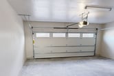 This single-floor garage, located at 1580 Main, offers a blend of functionality and modern design. The space is characterized by its clean, minimalist aesthetic with smooth white walls and a durable concrete floor. A sectional garage door with windows allows natural light to filter in, complementing the artificial lighting fixtures installed on the ceiling.

The garage is equipped with a state-of-the-art automatic door system, ensuring convenient access. Along the walls, you'll notice pre-installed mounting brackets, providing versatile options for shelving and tool organization. A side entry door offers additional access to the space.

The concrete flooring is sturdy and easy to maintain, capable of supporting heavy vehicles and equipment. High ceilings contribute to the spacious feel and offer potential for overhead storage solutions. The overall design prioritizes cleanliness and efficiency, making it an ideal space for not only parking vehicles but also for setting up a workshop or storing household items.

While the exact square footage is not provided, the garage appears to offer ample space for at least one vehicle plus additional storage or work areas. The thoughtful design elements and modern features make this garage a valuable addition to any property.