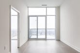 Located at 195 Deerfield Rd in Newmarket, Ontario, this thoughtfully designed one-bedroom, one-bathroom unit offers a clean, contemporary aesthetic throughout. Light-toned hardwood flooring runs continuously across the open layout, complementing the crisp white walls and tall ceilings that enhance the sense of space.

The open-concept living and kitchen area forms the heart of the unit. The kitchen is outfitted with warm natural wood cabinetry, stainless steel appliances including a built-in microwave, electric range, and refrigerator, all set against a simple white countertop with an undermount sink. The adjoining living area benefits from abundant natural light.

The bedroom is a bright, airy retreat highlighted by expansive floor-to-ceiling windows that frame wide, elevated views of the Newmarket skyline and surrounding landscape — a standout feature of the space. A dedicated closet with built-in hanging rods provides practical storage.

The hallway connects the living spaces efficiently and includes a ventilation panel, demonstrating attention to functional detail. The bathroom is finished in a clean, all-white palette featuring a full soaker tub with tiled surround, chrome fixtures, a toilet, and a modern vanity with a light countertop. Every room reflects a minimalist, move-in-ready design suited for comfortable urban living.