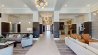 Located at 3000 Dominion Ridge Way in Morrisville, NC, this single-floor clubhouse is a masterfully designed community amenity space that blends contemporary style with functional versatility. The grand entrance corridor sets an impressive tone, featuring a herringbone-patterned tile floor, dark wood-clad columns, and a series of elegant sputnik chandeliers that draw the eye through the length of the hall toward glass double doors beyond.

The main lounge areas are bathed in natural light from floor-to-ceiling windows overlooking the outdoor pool area, with direct access through glass doors. Plush sectional and accent seating arrangements are complemented by built-in shelving, a marble-surround fireplace, and rich layered textures throughout.

The game room stands out with a full-size billiards table positioned beneath a striking teal geometric ceiling feature and bold pendant lighting, alongside a wet bar with a mounted flat-screen TV. A dedicated social lounge offers upholstered banquette seating, marble-top tables, gold pendant lights, and a multi-screen TV wall, perfect for gatherings.

The event kitchen and dining area features bold hexagonal tile flooring, a large stone-topped communal table with teal velvet seating, dark shiplap accent walls, and a fully equipped catering-style kitchenette.