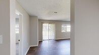 Located at 2 Austinville Rd SW in Decatur, Alabama, this single-story, 2-bedroom, 1-bathroom residence offers a well-organized and functional layout. The living room serves as the central gathering space, featuring rich dark hardwood-style flooring, neutral gray walls, and a textured ceiling. Large sliding glass doors with vertical blinds flood the room with natural light and provide direct access to the outdoors, while an additional window further brightens the space. The kitchen is a standout feature, showcasing white shaker-style upper cabinets, dark lower cabinets, a classic subway tile backsplash, and white appliances including a range and refrigerator. A built-in closet adjacent to the kitchen offers convenient storage. Both bedrooms are carpeted and finished with neutral tones; the primary bedroom is generously sized, while the second bedroom includes a window with outdoor views. The shared bathroom is clean and functional, equipped with a full tub-and-shower combination, a grab bar, and crisp white surrounds. A hallway connects the rooms efficiently, and a dedicated closet provides additional storage. The overall ambiance is clean, practical, and move-in ready.