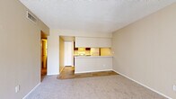 Located at 1750 E Bell Rd in Phoenix, AZ, this single-floor, 2-bedroom, 1-bathroom residence offers a practical and comfortable layout with a warm, neutral color palette throughout. The open-concept living room and kitchen area creates a welcoming central space, with plush carpeting in the living area transitioning to tile flooring in the kitchen. The kitchen is well-equipped with dark espresso cabinetry, ample upper and lower storage, a white electric range, refrigerator, and a pass-through counter that connects to the living space. Natural light filters in through vertical blinds in the living room, which also features a charming decorative entry door. Both bedrooms are carpeted and finished in soft beige tones, with vertical blinds providing light control. The spacious primary bedroom includes a dedicated closet with built-in shelving and rod. A second bedroom also offers closet access. The bathroom features a wide vanity with dark cabinetry, a large mirror, and tile flooring, complementing the consistent design language found throughout the home. A hallway connects the private areas of the residence, and a dedicated closet adds additional storage. Textured ceilings complete the interior aesthetic of this well-organized Phoenix home.
