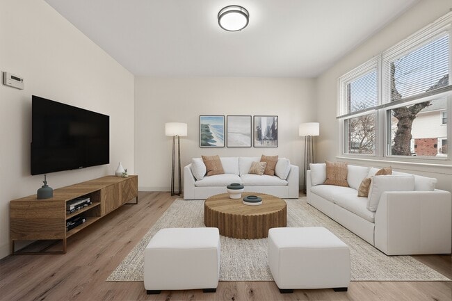 Luminoso y acogedor salón de apartamento con decoración moderna, grandes ventanales, cómodos sofás blancos y una elegante mesa de centro de madera, perfecto para relajarse y entretenerse. - Stony Brook Commons