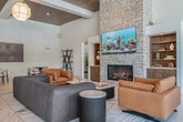 Located at 2015 E Springs Dr in Madison, WI, this expansive single-floor community space offers a refined blend of modern design and inviting functionality. The generous floor plan encompasses a living room and game room, unified by polished marble-look tile flooring that flows seamlessly throughout the main areas.

The living room is an architectural showpiece, boasting soaring ceilings with warm wood paneling and exposed beams, anchored by a dramatic floor-to-ceiling stone fireplace with a mounted flat-screen TV. Geometric pendant light fixtures add an elegant touch, while an abundance of large windows floods the space with natural light and frames outdoor views of a poolside area. A full kitchen bar with wood cabinetry, marble countertops, stainless steel appliances, and textured accent walls provides an ideal setting for entertaining. Comfortable seating arrangements, dining tables, and a statement indoor tree create a welcoming, resort-like atmosphere.

The game room offers a more casual, carpeted retreat featuring multiple billiard tables and a shuffleboard table, illuminated by stylish brass pendant lighting. Playful card suit artwork adorns the walls, and additional high-top seating with a wall-mounted TV makes it a versatile gathering space. Windows overlooking the outdoor pool area bring in natural light throughout.