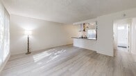 Located at 18427 Studebaker Rd in Cerritos, CA, this 2-bedroom, 1-bathroom single-floor residence offers a well-organized layout encompassing a living room, kitchen, two bedrooms, a full bathroom, and a hallway. Throughout the home, light hardwood-style flooring creates a clean, cohesive aesthetic that complements the neutral color palette on the walls and ceilings.

The living room is spacious and sun-drenched, featuring a large window with vertical blinds that frames views of the surrounding greenery. A pass-through opening connects the living area to the kitchen, enhancing the open feel of the space. The kitchen is well-appointed with white cabinetry, stone-look countertops, a mosaic tile backsplash, stainless steel appliances including a side-by-side refrigerator and gas range, a stainless steel range hood, and track lighting overhead. A sliding glass door in the kitchen provides direct outdoor access.

Both bedrooms are bright and comfortably sized, each featuring ceiling fans, windows with verdant outdoor views, and mirrored sliding closet doors that contribute to a sense of openness. The primary bedroom includes convenient access to the shared bathroom. The full bathroom is cleanly finished with a tub-shower combination, gray countertops, white cabinetry, and a small window for natural ventilation.
