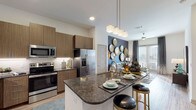 This well-appointed single-floor residence showcases a contemporary design with a seamless open-concept layout connecting the kitchen, dining, and living areas. The kitchen is a functional centerpiece, featuring wood-tone flat-front cabinetry extending to the ceiling, a white tile backsplash with under-cabinet lighting, stainless steel appliances including a French door refrigerator, electric range, and built-in microwave. A large island with dark granite countertops provides both workspace and bar-style seating with pendant lighting overhead. Light wood-look flooring flows throughout the main living areas, complementing the neutral wall palette accented by bold charcoal feature walls. The living room is anchored by large sliding glass doors that frame panoramic city views, allowing abundant natural light to fill the space. The bedroom offers plush carpeting, a soft teal accent wall, and windows with city views. A hallway connects the bedroom to a bathroom featuring marble-style tilework and a dark granite vanity. Recessed lighting and ceiling fans complete the polished, modern ambiance throughout.