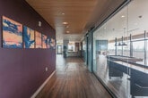 Located at 580 Arastradero Rd in Palo Alto, CA, this thoughtfully designed amenity floor offers a generous and versatile layout spanning a substantial single level. The space is defined by a central corridor finished with rich hardwood flooring and a striking slatted wood ceiling, flanked by floor-to-ceiling glass partitions with sliding barn-style doors that provide visual connectivity throughout.

The fully equipped kitchen features sleek, striated wood cabinetry, a subway tile backsplash, stainless steel appliances including a French door refrigerator and wine cooler, and clean white countertops — ideal for catering and communal dining.

Adjacent lounge areas are elegantly furnished with contemporary seating, soft carpeting, and bold accent walls in deep plum and vivid teal, creating distinct yet cohesive social zones. A dedicated game room houses a full-size billiard table beneath dramatic pendant lighting, framed by expansive floor-to-ceiling windows that flood the space with natural light.

The outdoor terrace is a standout feature, offering sweeping panoramic views of the surrounding treetops and the rolling hills of the Bay Area. Finished with concrete decking and iron railings, the terrace provides generous space for outdoor seating and entertaining, with the natural landscape serving as a breathtaking backdrop throughout.
