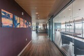 Located at 580 Arastradero Rd in Palo Alto, CA, this thoughtfully designed amenity floor offers a generous and versatile layout spanning a substantial single level. The space is defined by a central corridor finished with rich hardwood flooring and a striking slatted wood ceiling, flanked by floor-to-ceiling glass partitions with sliding barn-style doors that provide visual connectivity throughout.

The fully equipped kitchen features sleek, striated wood cabinetry, a subway tile backsplash, stainless steel appliances including a French door refrigerator and wine cooler, and clean white countertops — ideal for catering and communal dining.

Adjacent lounge areas are elegantly furnished with contemporary seating, soft carpeting, and bold accent walls in deep plum and vivid teal, creating distinct yet cohesive social zones. A dedicated game room houses a full-size billiard table beneath dramatic pendant lighting, framed by expansive floor-to-ceiling windows that flood the space with natural light.

The outdoor terrace is a standout feature, offering sweeping panoramic views of the surrounding treetops and the rolling hills of the Bay Area. Finished with concrete decking and iron railings, the terrace provides generous space for outdoor seating and entertaining, with the natural landscape serving as a breathtaking backdrop throughout.