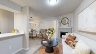 This thoughtfully designed 1-bedroom, 1-bathroom residence offers a comfortable and cohesive living experience across a single floor. The open-concept living and dining area serves as the heart of the home, anchored by a painted brick fireplace with a classic white mantel that adds warmth and character. Light wood-style flooring flows throughout, complementing the neutral tones of the walls and textured ceilings. Vertical blinds on a sliding door allow for natural light control and provide access to the outdoors.

The kitchen features crisp white cabinetry, stainless steel appliances including a refrigerator, range, and over-the-range microwave, and a generous quartz-topped breakfast bar with an undermount sink — ideal for both meal prep and casual dining.

The bedroom is a private retreat highlighted by a bold accent wall, a ceiling fan with light fixture, and a natural window that brings in soft daylight. Light flooring continues here, enhancing the airy feel of the space.

The bathroom is finished with gray shaker-style cabinetry, a white countertop vanity, a large mirror, overhead storage, and a tub-shower combination with classic white tile surround. Every room reflects a clean, modern aesthetic with practical functionality throughout.