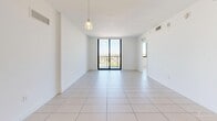 Located at 1900 Southwest 8th Street in Miami's vibrant Little Havana neighborhood, this 3-bedroom, 2-bathroom unit offers a clean, modern aesthetic throughout its single-floor layout. Light-toned large-format ceramic tile flooring runs consistently through every room, lending a cohesive, airy feel to the entire space.

The combined living and dining area is the heart of the home, featuring bright white walls, a contemporary pendant light fixture, and a full-height sliding glass door that opens to a private balcony with sweeping city views — flooding the space with natural light.

The kitchen is well-appointed with warm wood-toned cabinetry, a white tile backsplash, light countertops, and a full suite of stainless steel appliances including a refrigerator, range, and microwave. Track lighting above adds functional illumination.

Each of the three bedrooms is finished in the same clean white palette with tile flooring and large windows that frame outdoor views. The bedrooms are served by three closets, including louvered bi-fold door closets and a walk-in closet with built-in shelving and hanging rods.

The two bathrooms are outfitted with tub-shower combinations, white tile surrounds, wood-toned vanities, and light quartz countertops, maintaining the home's consistent modern style throughout.