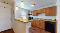 Located at 2096 Randy Scott Dr in West Carrollton, Ohio, this two-floor home offers a practical and well-organized layout designed for comfortable everyday living. The kitchen is equipped with warm honey-toned cabinetry, granite-style countertops, black appliances including a range and dishwasher, a double-basin sink, and hardwood flooring. A peninsula breakfast bar with pendant lighting provides additional prep and dining space, while a window allows natural light to brighten the room. The living area is generously proportioned, featuring plush carpeting, a sliding glass door that opens to a private outdoor patio, and ample room for seating and entertaining. The bedrooms offer carpeted floors, ceiling fans or pendant lighting, and windows that bring in natural light. Each bedroom provides comfortable accommodations with practical storage options. The bathroom features hardwood flooring, a white vanity with a framed mirror, and a full tub-shower combination. Throughout the home, neutral wall tones create a clean, versatile backdrop that complements each space. The overall layout across two floors provides a clear separation between living and sleeping areas, making this a functional and inviting residence in West Carrollton.
