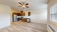 This efficiently designed 1-bedroom, 1-bathroom unit offers a thoughtful layout across a single floor, combining functionality with modern aesthetics. The open-concept kitchen and living area serves as the heart of the unit, featuring warm wood-tone flat-panel cabinetry, clean white countertops, and a full suite of stainless steel appliances including a refrigerator, electric range, built-in microwave, and dishwasher. A ceiling fan with lighting anchors the living space, while a windowed entry door invites natural light and outdoor views into the area. Light-toned luxury vinyl plank flooring extends seamlessly throughout the entire unit, creating a cohesive and easy-to-maintain surface. The bedroom is a comfortable, well-proportioned room with a window providing natural light and direct access to a dedicated closet. The bathroom is finished with a warm wood-tone vanity, white countertop, a large mirror with overhead lighting, and matching flooring that ties the space together. Neutral wall tones throughout create a clean, move-in-ready canvas. The unit also includes a private entry with a windowed door and a wall-mounted HVAC unit in the living area, offering individual climate control.
