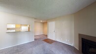 Located at 3045 Woodland Hills Dr in Colorado Springs, Colorado, this single-floor residence offers a functional and comfortable layout throughout. The living area serves as the heart of the home, featuring plush carpeting, a wood-burning fireplace, and a pass-through window connecting to the kitchen, creating an open and connected feel. A wood-panel entry area near the front door adds a warm touch at the threshold. Baseboard heating runs along the walls, ensuring consistent warmth, and a textured ceiling is present throughout the common areas. The galley-style kitchen is efficiently designed with warm wood cabinetry, a double sink, laminate countertops, and wood-look flooring. White appliances including a refrigerator, electric range, and microwave are included, along with a dishwasher. A set of bi-fold doors at the end of the kitchen provides additional storage. The bedroom is generously sized with soft carpeting, a large window that allows ample natural light and views of surrounding greenery, and baseboard heating. The full bathroom features a tub and shower combination with white tile surround, a wood-toned vanity with a single sink and stone-look countertop, a large mirror, and wood-look flooring. The space is rounded out by a window in the living area that brings in additional natural light.