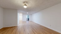 Located at 2929 Landrum Dr SW in Atlanta, Georgia, this two-floor home offers a clean, updated interior designed for comfortable living. The main living area is open and airy, featuring light-toned hardwood-style flooring, white walls, and a textured ceiling with a ceiling fan, creating a bright and welcoming atmosphere. Vertical blinds along a sliding glass door allow natural light to filter in while offering privacy. The kitchen is a standout feature, showcasing granite countertops, gray shaker-style cabinetry, a white tile backsplash, stainless steel appliances including a range and dishwasher, and hardwood-style flooring — all illuminated by a window overlooking the exterior. A connecting hallway leads to the various rooms, offering a practical and well-organized layout. The bedrooms are carpeted for comfort, with multiple closets providing ample storage, and windows that bring in natural light. The bathroom features a tiled soaking tub and hardwood-style flooring, maintaining a clean, functional design. Throughout the home, the consistent use of white trim, neutral tones, and updated finishes contribute to a cohesive and move-in-ready aesthetic across both floors.