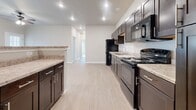 This single-story, 3-bedroom, 2-bathroom home offers a functional and modern layout designed for comfortable everyday living. The kitchen serves as a focal point of the home, featuring dark espresso cabinetry, light granite-style countertops, a full suite of black appliances including a refrigerator, range, dishwasher, and microwave, all set atop light wood-style flooring. A peninsula provides additional counter space and creates a natural transition into the open living area.

The three bedrooms are finished with soft wall-to-wall carpeting, ceiling fans, and windows that allow natural light to fill each room. The primary bedroom offers a generous footprint with ample space for furnishings. A dedicated laundry room with wire shelving and light wood-style flooring adds everyday convenience.

Both bathrooms are finished with matching dark cabinetry, light granite-style countertops, and wood-style flooring. One bathroom features a tub-shower combination, while the other offers a walk-in shower with tiled surround.

A long, well-lit hallway connects the bedrooms and bathrooms, finished with recessed lighting and clean white trim throughout. Neutral tones, recessed lighting, and consistent finishes give the entire home a cohesive, move-in-ready appearance.