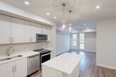 Located on Elbow Drive SW in Calgary, this thoughtfully designed one-bedroom, one-bathroom unit offers a contemporary open-concept layout finished with warm wood-look flooring and crisp white walls throughout. The kitchen is a standout feature, showcasing sleek white cabinetry extending to the ceiling, a full suite of stainless steel appliances, a tile backsplash, and a large white quartz island illuminated by elegant glass pendant lights — all flowing seamlessly into the bright living area, which benefits from natural light through a front-facing window and door. A versatile den provides additional flexible space suitable for a home office or guest room. The primary bedroom is a comfortable, well-proportioned retreat with its own closet access and wood-look flooring. The full bathroom is clean and modern, featuring a soaker tub with overhead shower, tile flooring, and recessed lighting. A dedicated laundry room with stacked washer and dryer adds everyday convenience. Two closets and a hallway round out the functional layout, making excellent use of the available space. The overall aesthetic is fresh, modern, and move-in ready.