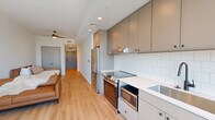 Located at 1405 Spring St NW in Atlanta's vibrant Midtown neighborhood, this contemporary studio offers a thoughtfully designed single-floor layout that maximizes every inch of its compact footprint. Light hardwood flooring runs throughout, complementing the clean white walls and recessed lighting that keep the space feeling bright and open.

The galley-style kitchen is a standout feature, outfitted with sleek grey cabinetry extending to the ceiling, white subway tile backsplash, quartz countertops, stainless steel appliances including a glass-top range, built-in microwave, and a full-size refrigerator, along with a matte black faucet over a stainless undermount sink.

The living area is airy and minimalist, with ample wall space and light hardwood floors that flow seamlessly from the kitchen. A ceiling fan adds comfort to the space. A narrow hallway connects the living and sleeping areas, with the bedroom positioned at the far end, bathed in natural light through large floor-to-ceiling windows that frame city views of the Atlanta skyline.

The bathroom features a warm wood-toned vanity with a white quartz countertop, a large mirror with modern lighting, matte black hardware, and elegant herringbone-patterned tile flooring, rounding out this well-appointed urban residence.