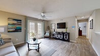 Located at 2212 Charing Wood Dr in Mobile, Alabama, this well-appointed 2-bedroom, 2-bathroom single-story home offers a thoughtfully designed layout that maximizes comfort and functionality. The living room serves as the heart of the home, featuring light wood-look flooring, a ceiling fan, a textured ceiling, and a set of French doors that flood the space with natural light and provide access to the outdoors. The adjacent dining area is accented by a pendant light fixture and chair-rail molding, creating a defined yet open space. The galley-style kitchen is equipped with white cabinetry, light stone-look countertops, a skylight, and black appliances, offering ample storage and workspace. The spacious primary bedroom is carpeted and includes a ceiling fan, a large window with natural light, and access to a walk-in closet with wire shelving. The bathrooms are finished with white vanity cabinetry, marble-look countertops, large mirrors, and wood-look tile flooring. A hallway connects the rooms efficiently, and two closets provide generous storage throughout. Neutral warm-gray tones carry consistently across the home, lending a cohesive and inviting ambiance throughout.