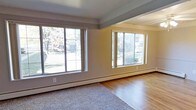 This single-floor space offers a well-organized layout with a clean, functional design throughout. The living area is a standout feature, bathed in natural light courtesy of multiple large sliding windows that frame views of lush, tree-lined outdoor surroundings. Warm hardwood flooring transitions into plush carpeting, defining the distinct zones of the space. Baseboard heating runs along the perimeter of the living area, ensuring year-round comfort.

The kitchen is efficiently laid out with ample white cabinetry extending to the ceiling for generous storage. A stainless steel sink, laminate countertops, a gas range with overhead ventilation, and a full-size refrigerator provide all the essentials in a compact, well-organized footprint.

The bedroom is a spacious, carpeted retreat with neutral gray walls that lend a calm and restful ambiance. A walk-in closet with built-in shelving offers excellent organization, while an additional closet provides further storage flexibility. An open passage connects seamlessly to the rest of the unit, enhancing the overall sense of flow. Together, the rooms create a cohesive, move-in-ready space that balances practicality with comfortable, everyday living.