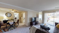 This single-floor residence offers a thoughtfully organized layout that balances comfort and functionality throughout. The living room is a welcoming central space, featuring crown molding, neutral-toned carpet, and a ceiling fan, with a wide wall ideal for an entertainment setup. The room flows naturally into the dedicated dining area, which is accented by a ceiling fan and provides ample space for a full dining table and sideboard. The kitchen is practical and well-equipped, showcasing white cabinetry, a gas range, a full-size refrigerator, and light hardwood-style flooring. A notable feature is the in-unit washer and dryer, conveniently located within the kitchen area. The primary bedroom is generously proportioned with plush carpet, a large closet, and a calm, neutral palette that promotes rest. A second bedroom offers similar comfort with its own closet and soft carpeting, suitable as a guest room or home office. The bathroom is clean and efficiently designed, featuring granite-style countertops, white cabinetry, a medicine cabinet mirror, and a shower-tub combination. Natural light filters throughout the unit via multiple windows, contributing to the bright and airy overall ambiance of this well-maintained residence.
