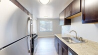 This single-floor, 3-bedroom, 2-bathroom residence offers a practical and comfortable layout designed to maximize livability. The living area is bright and open, featuring plush carpeting, neutral gray walls, and large sliding glass doors fitted with vertical blinds that lead to a private balcony with outdoor views — allowing abundant natural light to fill the space. A ceiling fan enhances comfort in the generously sized primary bedroom, which also features soft carpeting and ample room for furnishings. The additional bedrooms are well-proportioned, each with carpeted floors and windows with vertical blinds providing natural light. The galley-style kitchen is thoughtfully appointed with rich dark-wood cabinetry, light granite countertops, a stainless steel sink, and a full suite of stainless steel appliances including a gas range, refrigerator, and microwave. Light wood-style flooring runs through the kitchen and connects to the dining area. The two bathrooms include one with a full tub-shower combination clad in clean white tile. A dedicated walk-in closet with dual hanging rods provides excellent storage. Additional features include in-unit laundry hookups, two hallways connecting the layout, and a dedicated entrance, making this a well-organized and functional home.