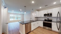 Located at 800 Federal Rd in Brookfield, Connecticut, this single-floor residence offers a well-appointed, modern living experience with high-quality finishes throughout. The open-concept layout seamlessly connects the kitchen and living area, creating a bright and spacious feel enhanced by recessed lighting and warm hardwood-style flooring that flows throughout the main living spaces.

The kitchen is a standout feature, showcasing crisp white shaker cabinetry, dark granite countertops, and a classic subway tile backsplash. Stainless steel appliances — including a range, over-the-range microwave, and dishwasher — complement the sleek peninsula with pendant lighting, which doubles as a functional prep and gathering space. A large window in the adjacent living area invites natural light, further brightening the open floor plan.

The bathroom is elegantly finished with a bold navy double-vanity, marble-style countertops, a large mirror, and light wood flooring, offering a striking contrast to the otherwise neutral palette. The bedroom features plush carpeting and a well-organized closet with built-in shelving, providing ample storage. Crown molding throughout adds a refined architectural touch, tying together the clean, contemporary aesthetic of this thoughtfully designed residence.