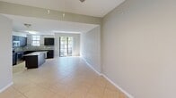 This contemporary townhouse in Miramar, FL offers 1170 square feet of living space across three floors. The property features 2 bedrooms, including a 150 sq ft primary bedroom, and 3 bathrooms. The ground floor houses a spacious garage with a modern overhead door system. The main living area showcases an open-concept design, combining the kitchen and living room. The kitchen boasts dark wood cabinetry, stainless steel appliances, and granite countertops with a complementary backsplash. Large windows and sliding glass doors in the living area provide ample natural light and outdoor access. Bedrooms feature plush carpeting and ceiling fans, with the primary bedroom offering an en-suite bathroom. Bathrooms are equipped with modern fixtures, including oval mirrors and granite vanity tops. The property includes two staircases for easy floor access, and two closets for additional storage. Neutral color schemes and tiled flooring in common areas contribute to a clean, contemporary aesthetic throughout the home.